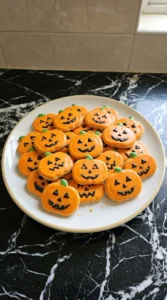 Halloween Pumpkin Cookies Royal Icing finished with orange icing green stems and varied black faces