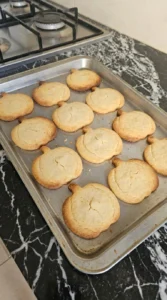 Halloween Pumpkin Designs step showing twelve pumpkin sugar cookies with pale centers and golden edges