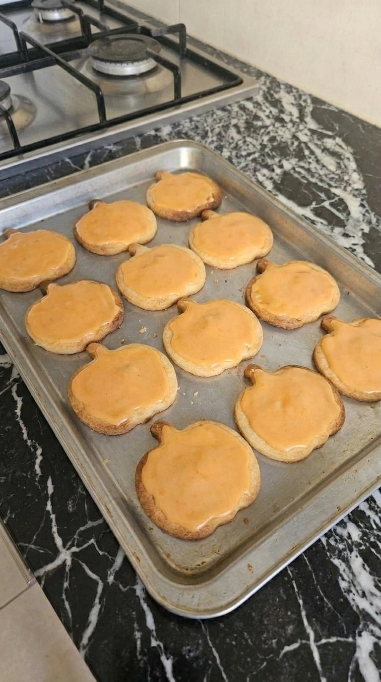 Halloween Pumpkin Designs step showing twelve cooled pumpkin cookies covered with smooth orange glaze