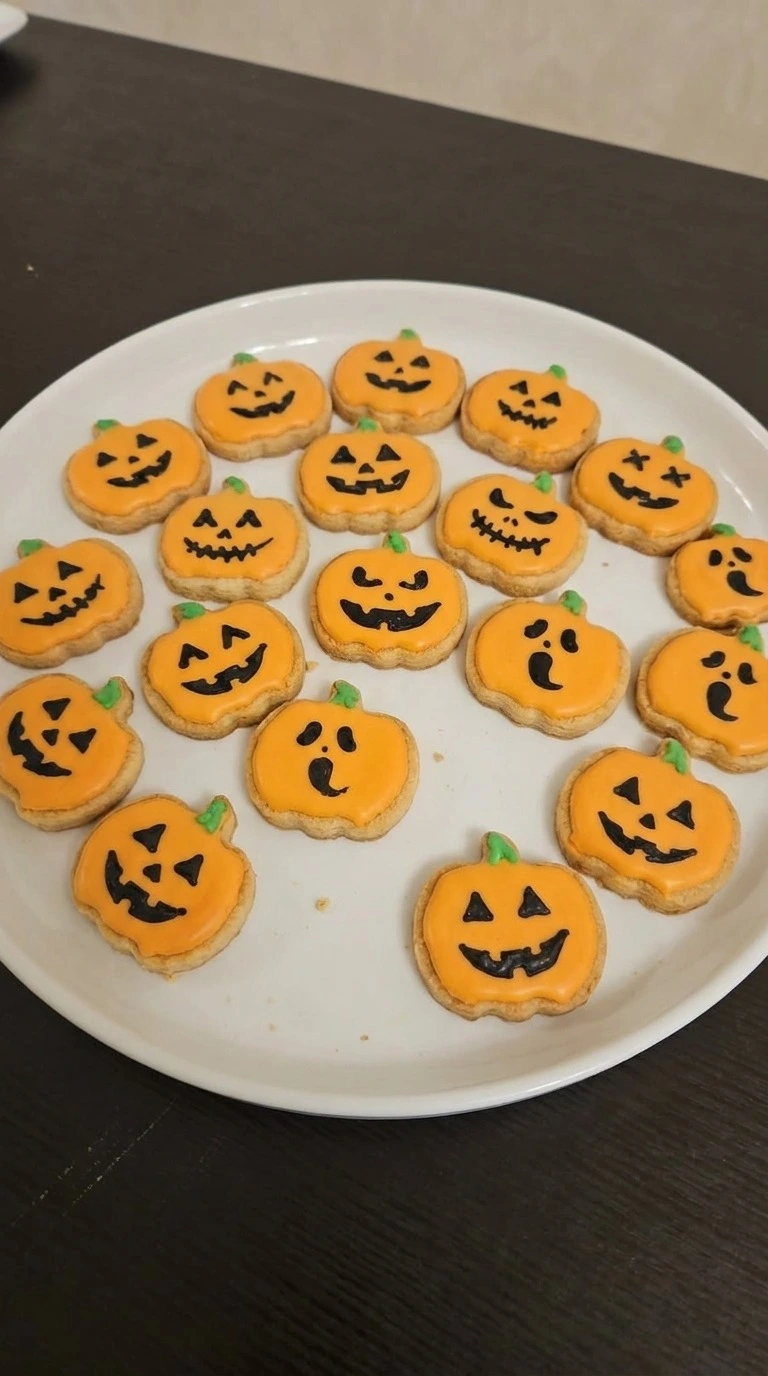 Halloween Pumpkin Painting shown as orange pumpkin sugar cookies with hand-painted black faces on a white Recipe focus: halloween pumpkin painting ideas easy.