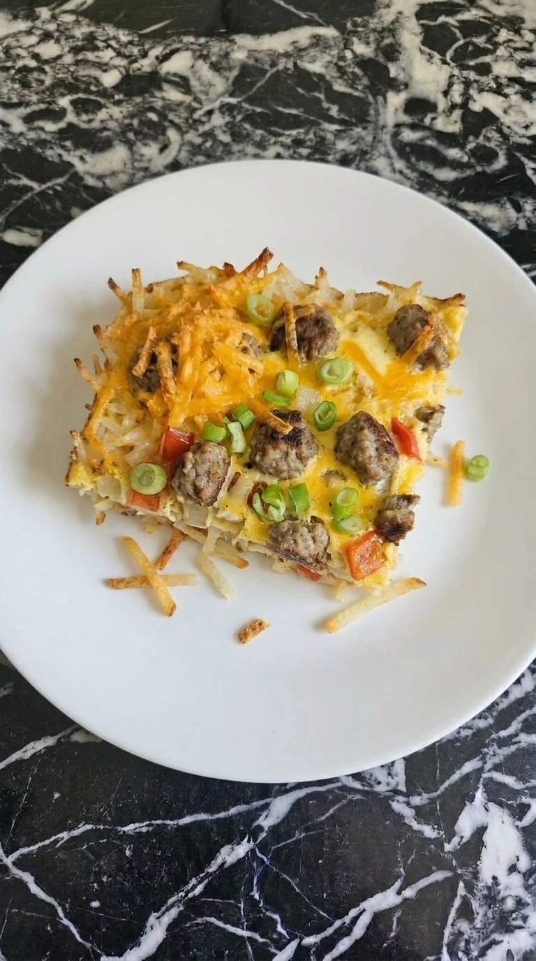 Hashbrown Breakfast Casserole slice showing potato strands, sausage, egg and melted cheddar Recipe focus: easy breakfast casserole.