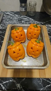 Orange Halloween Party Food step showing four carved orange bell peppers lightly pre-baked
