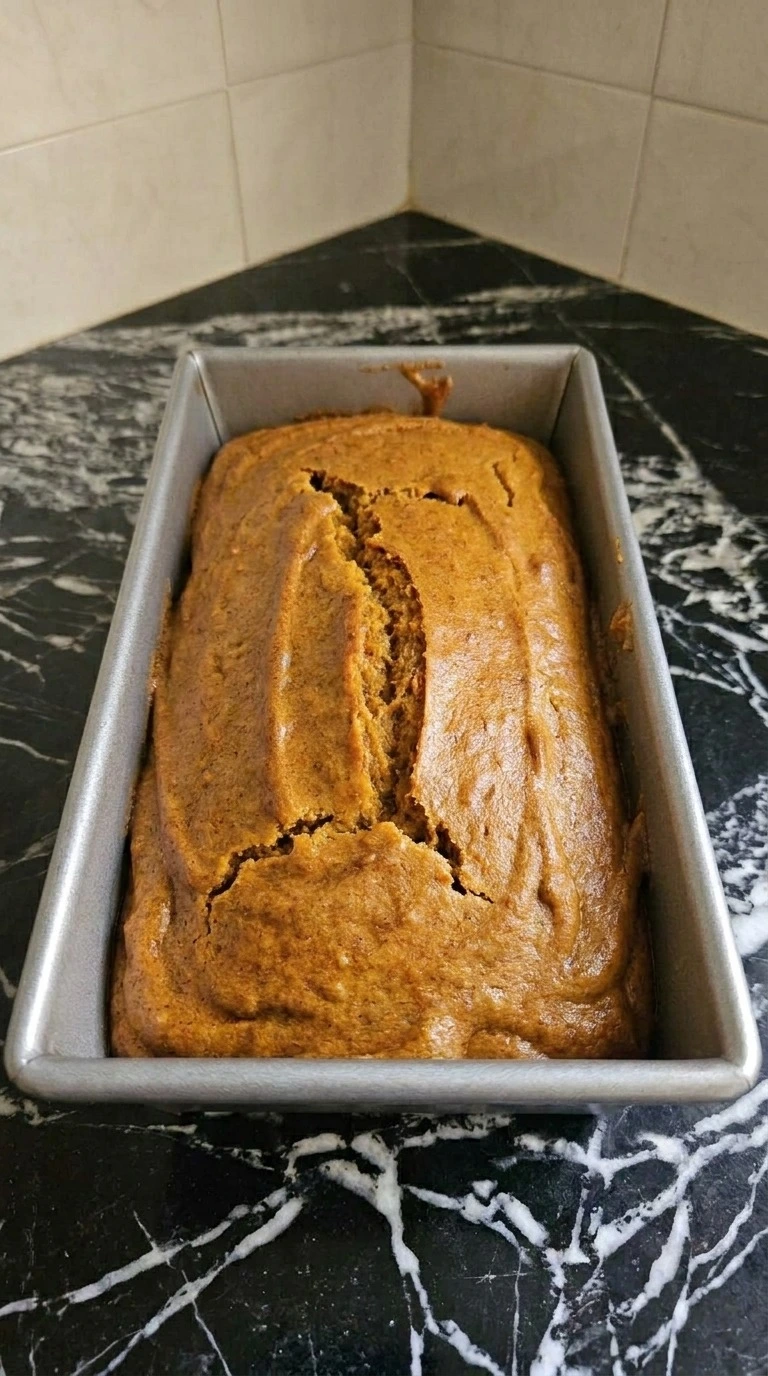 Almond Flour Pumpkin Bread baked with an amber-gold cracked top and slightly pulled edges in the loaf pan Recipe focus: gluten free pumpkin bread recipe.