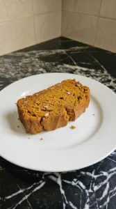 Almond Flour Pumpkin Bread slice showing moist orange crumb and a naturally cracked amber crust on a white plate Recipe focus: dairy free pumpkin bread.
