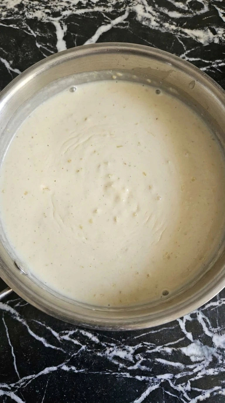 Smooth garlic Parmesan Alfredo sauce in a saucepan for Chicken Alfredo Bake Recipe focus: easy chicken alfredo bake.
