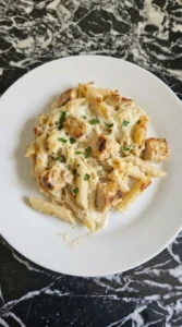 A plated serving of Chicken Alfredo Bake showing creamy penne, golden chicken and melted mozzarella Recipe focus: easy chicken alfredo bake.