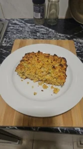 Cornbread Dressing served on a white plate with a golden top and moist herb-speckled center Recipe focus: cornbread dressing recipe.