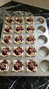 Cranberry Brie Bites filled with cubes of French Brie, whole berry cranberry sauce and chopped pecans before Recipe focus: thanksgiving cranberry brie bites.