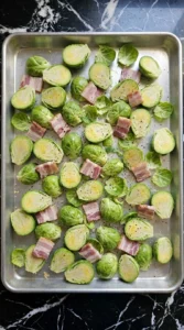 Roasted Brussels Sprouts with Bacon arranged raw on a sheet pan with olive oil and chopped bacon Recipe focus: roasted brussels sprouts with bacon recipe.