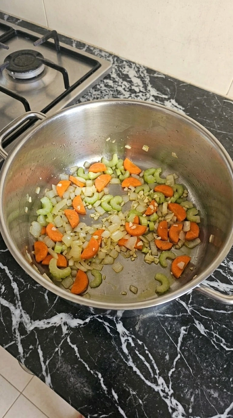 Turkey Noodle Soup vegetables softening with olive oil and minced garlic in a large pot. Recipe focus: easy turkey noodle soup.